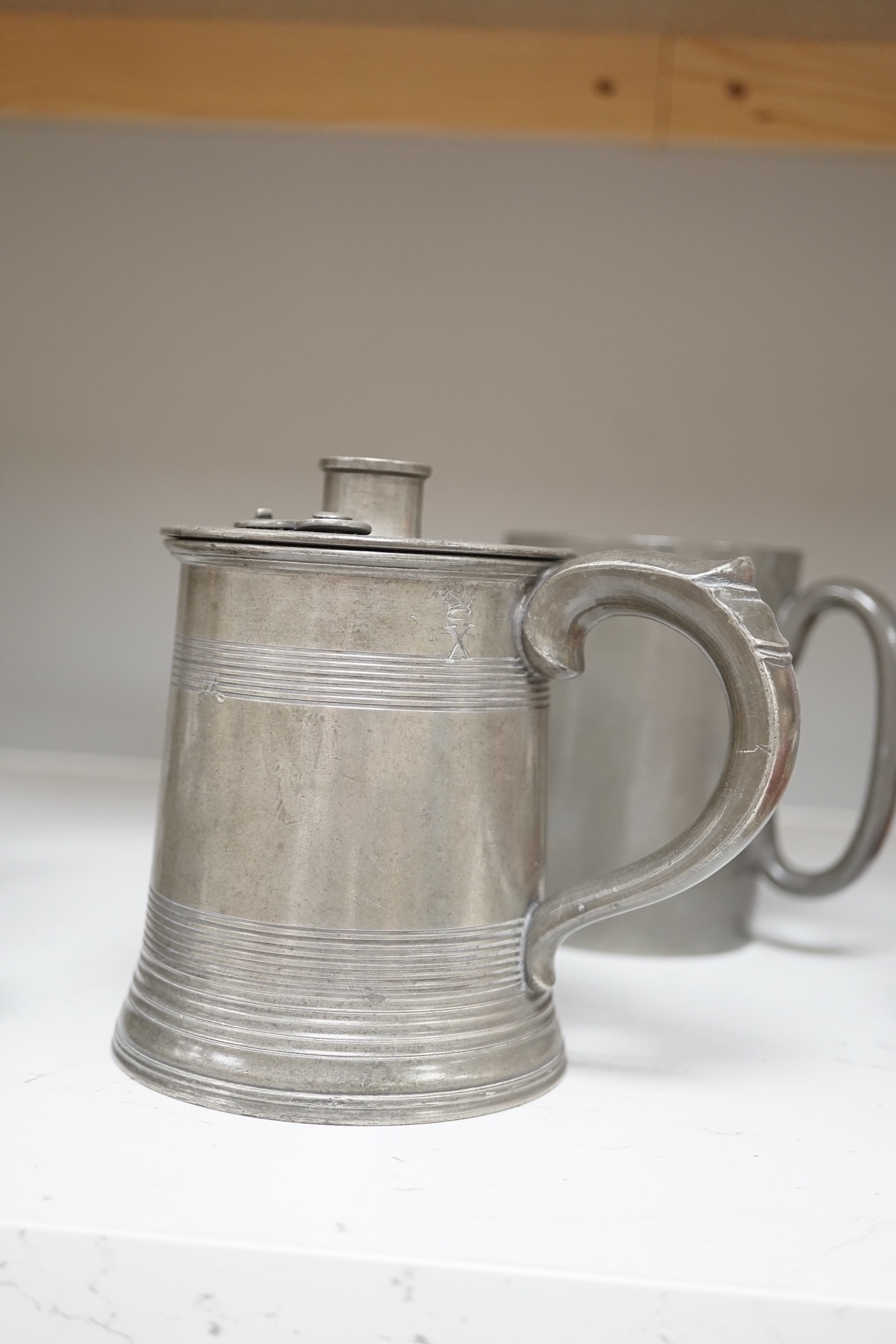 Six items of 18th century and later pewter including a jug, candlesticks, a pint measure, and a bronze hand bell, 24cm high. Condition - fair.